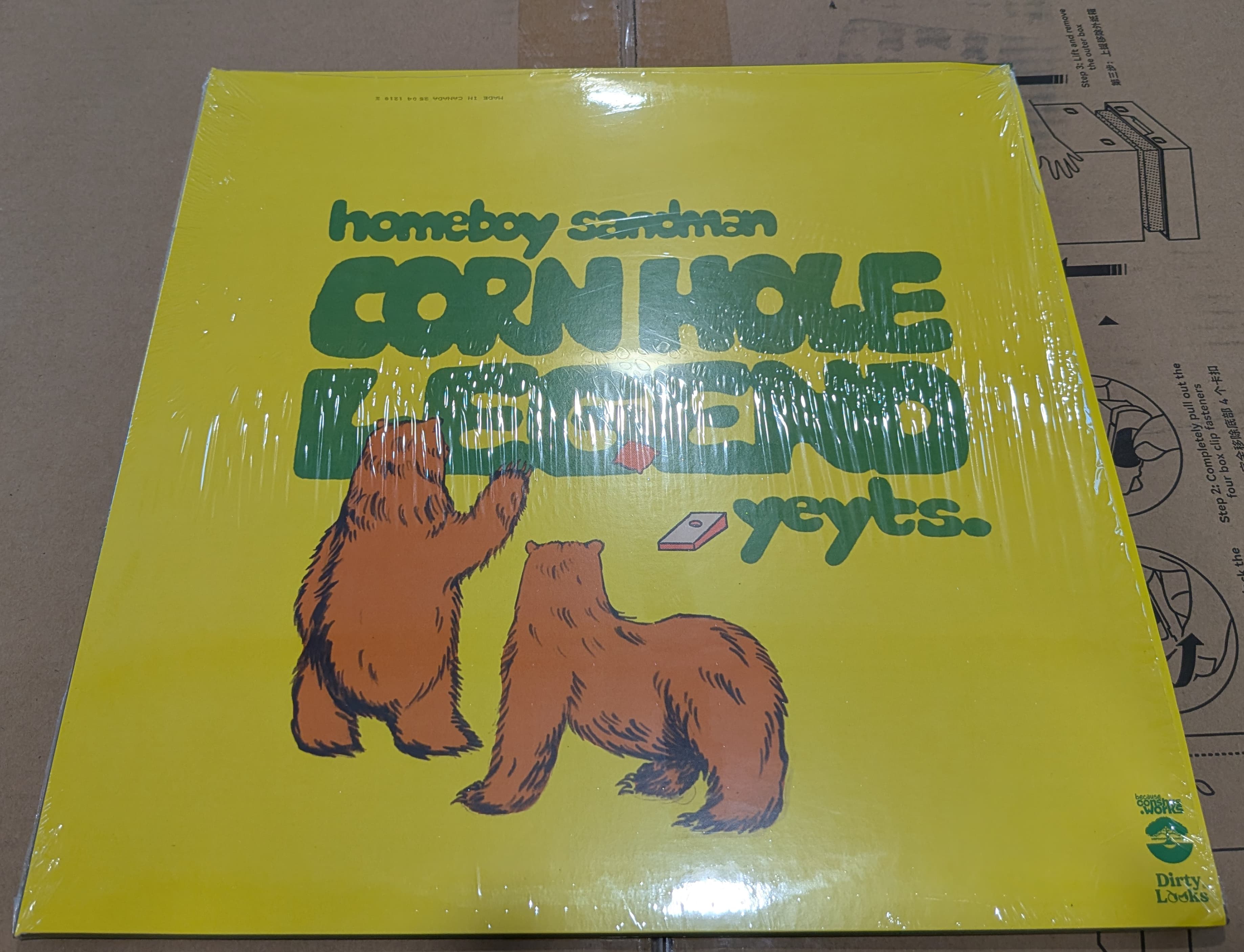 A yellow album cover featuring two cartoon bears playing cornhole with the green text 'homeboy sandman CORN HOLE LEGEND yeyts.'